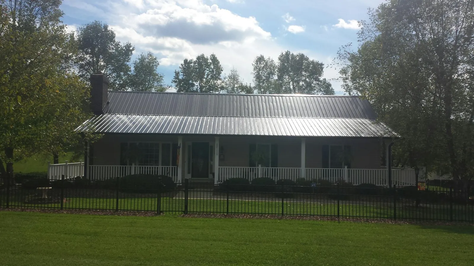Gray metal roof on a brick ranch with a full width front porch — Gutter Guard Installation work by our crew in Commerce