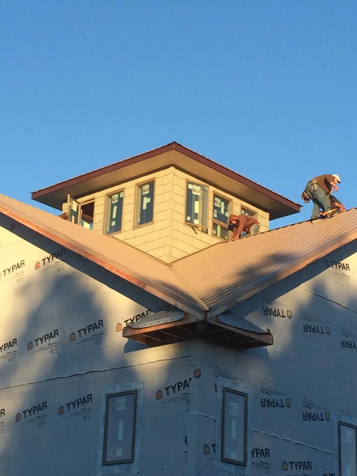 Roofers working around a rooftop cupola on a new metal roof at sunset — Roof Waterproofing in Commerce by Roofing Brothers